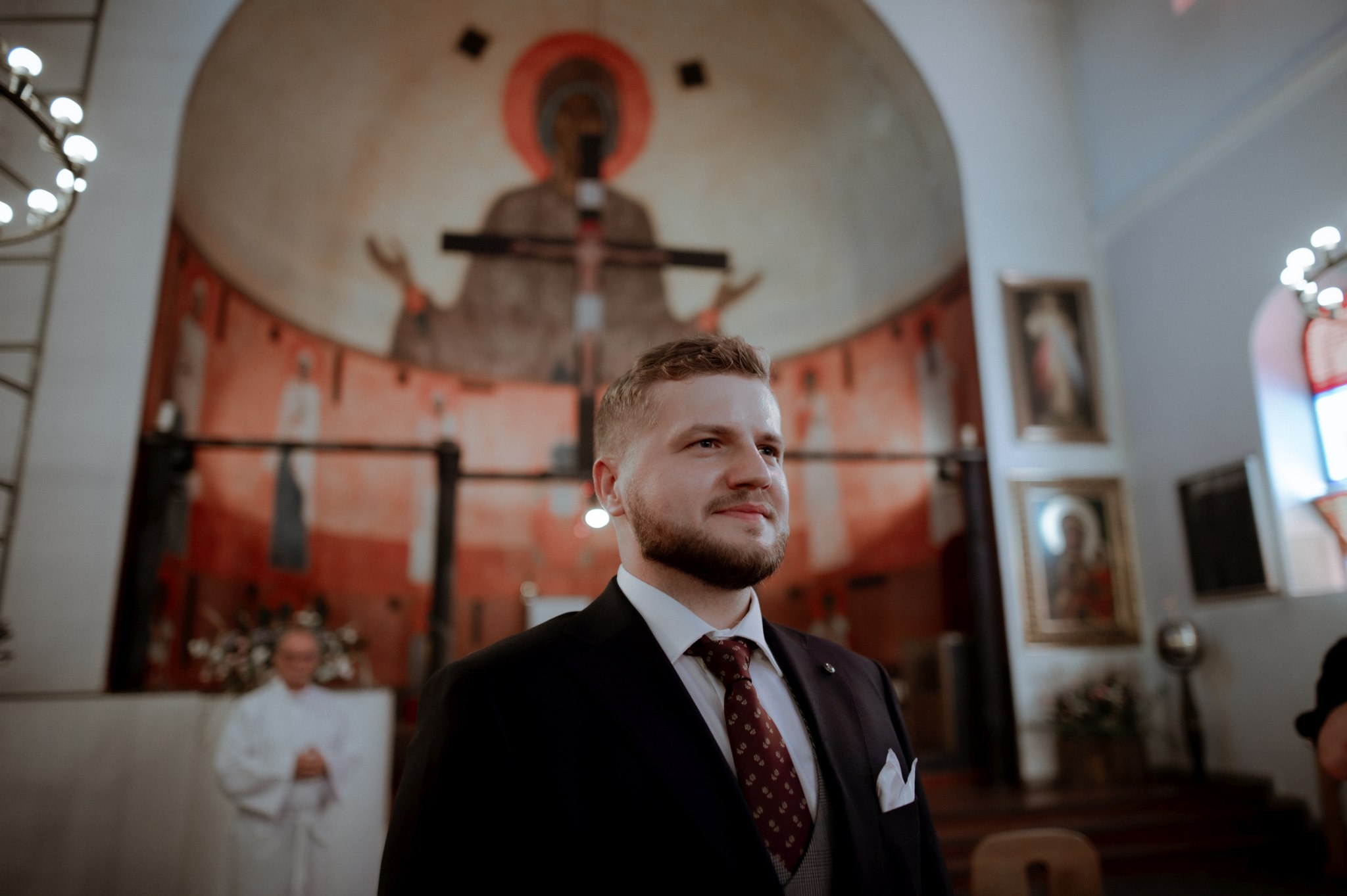 wzruszony pan młody patrzy jak tata prowadzi pannę młodą do ołtarza
